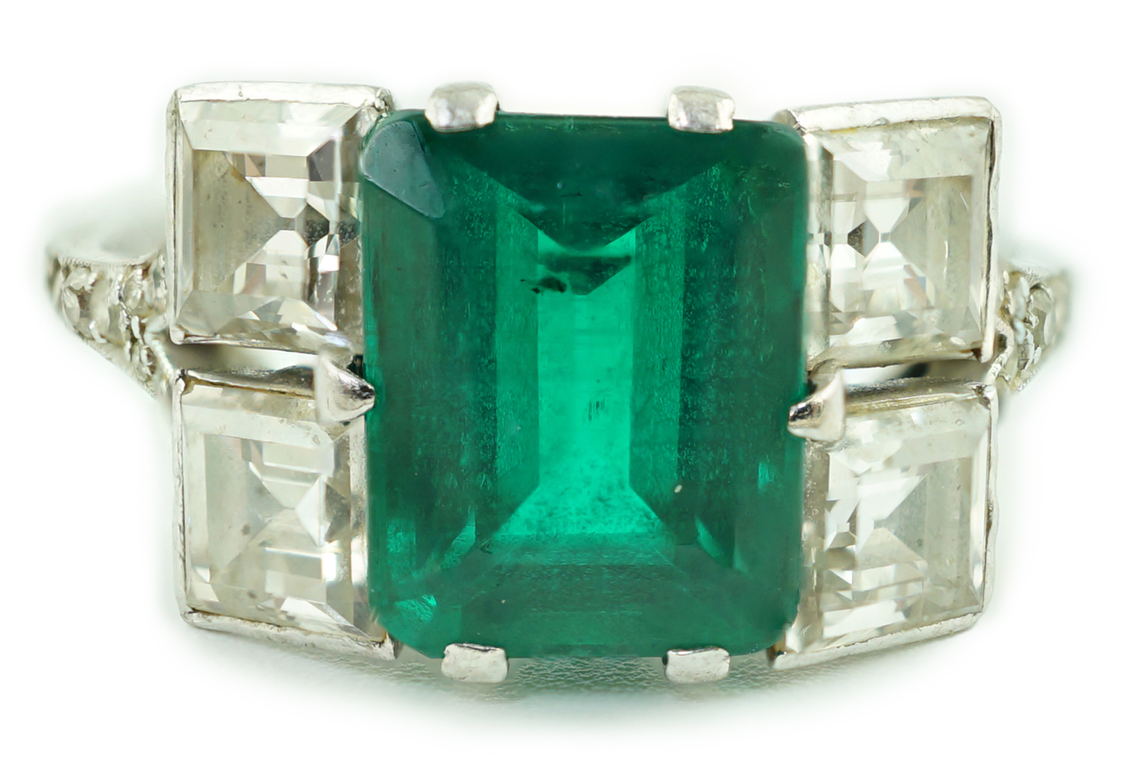An Art Deco platinum, emerald and square cut diamond dress ring, with diamond chip set shoulders